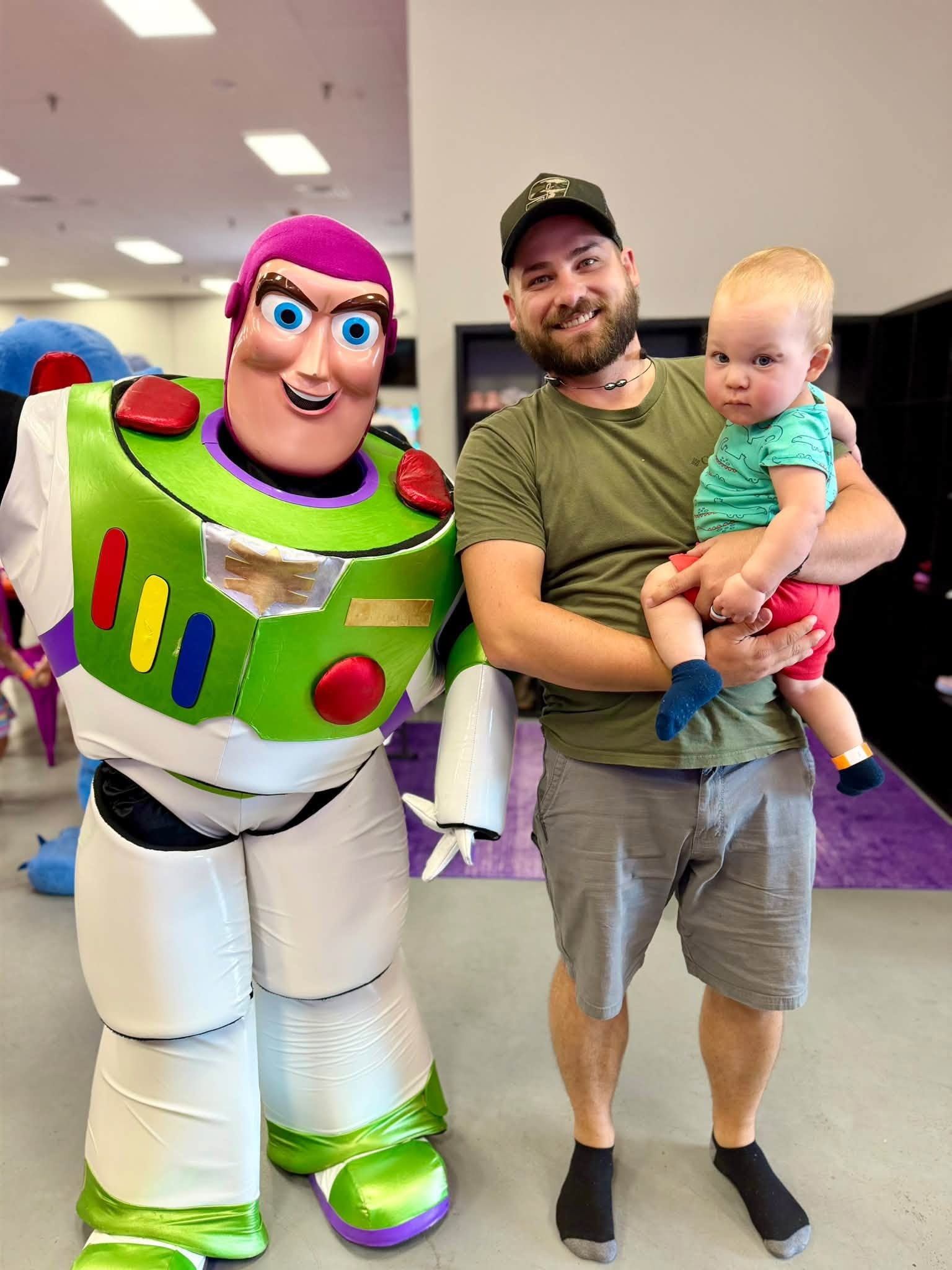 Dad and baby posing with Buzz Lightyear at Plum Krazy Play