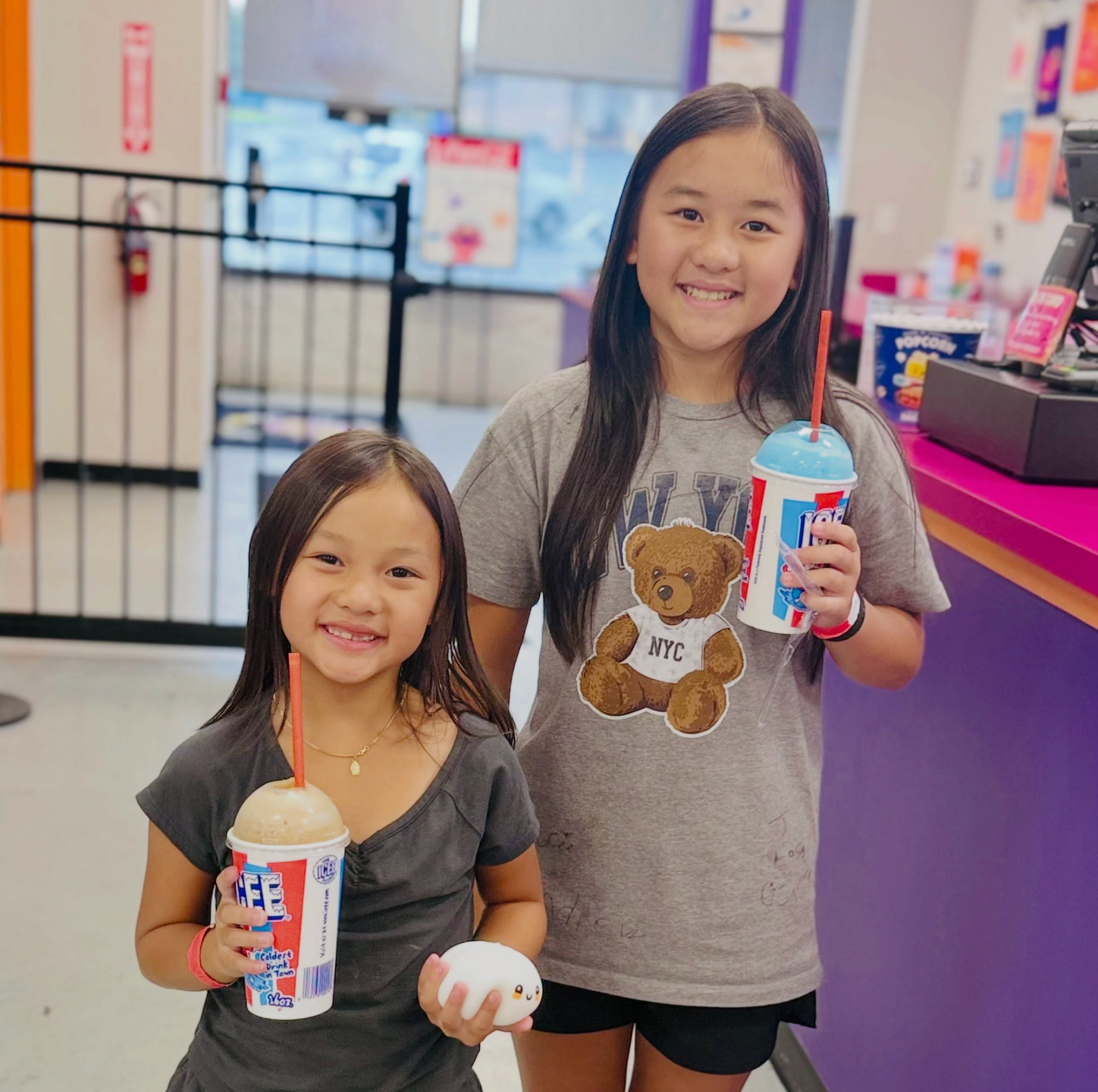 Two girls smiling with ICEE drinks at Plum Krazy Play