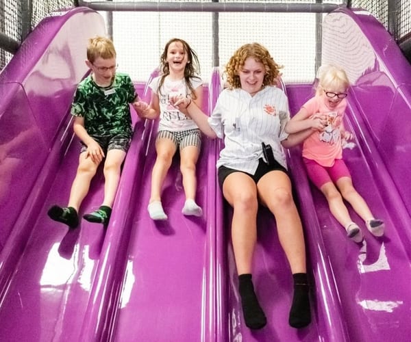 Kids on colorful indoor slides at Plum Krazy Play