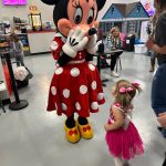 A little girl standing next to minnie mouse.