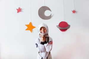 A child dressed as an astronaut in front of some decorations.