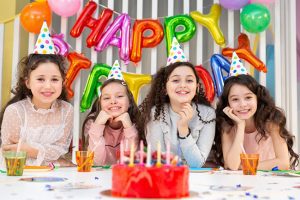 A group of girls sitting at the table with birthday cake.