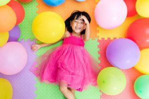 A little girl laying on the floor with balloons