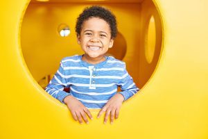 A young boy is smiling while sitting in the tunnel.