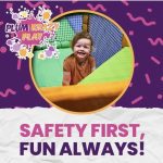 A child is smiling in the corner of an indoor playground.